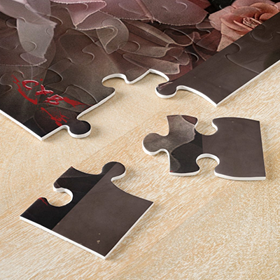 Close-up of the thick pieces of an artistic puzzle by Cyb, arranged on a light-colored wooden table.